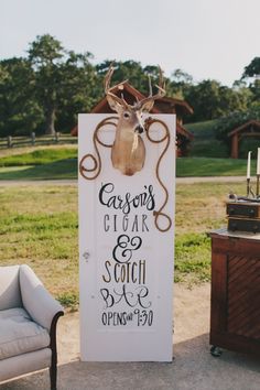 a white sign with a deer head on it sitting next to a chair and table