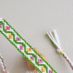 a green and pink bracelet with two tassels