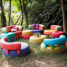 an assortment of colorful tires are arranged in the grass near trees and bushes, as if they were made from old tires