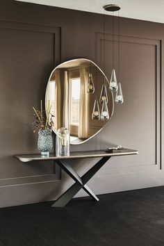 a table with a mirror and vases on it in front of a brown wall