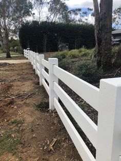 a white picket fence in front of some trees