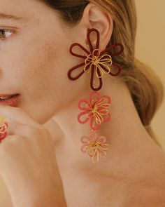 a woman wearing red and gold flower earrings