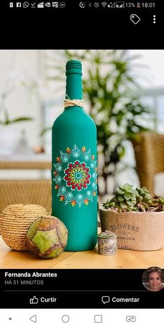 a green bottle sitting on top of a wooden table next to a potted plant