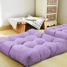 two purple futons sitting on top of a wooden floor next to a dresser