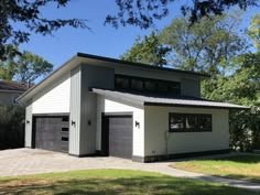 a two car garage sits in the middle of a yard with grass and trees around it