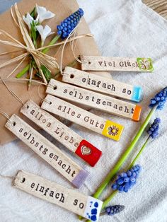 several wooden tags with words on them sitting next to flowers and a piece of paper