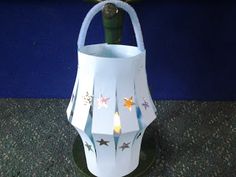 a white paper lantern with stars on it and a green stick sticking out of the top