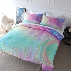 a bed with colorful comforters and pillows in a room next to a table on the floor