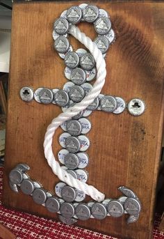 a cross made out of beer caps on top of a wooden board with white string