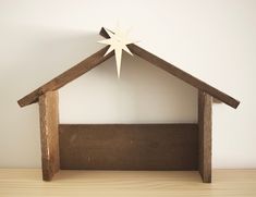 a wooden nativity scene with a star above the manger, against a white wall