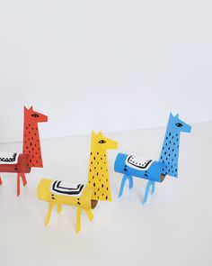 four colorful wooden animals sitting on top of a white table