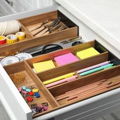 an open drawer filled with lots of crafting supplies on top of a white counter