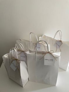 several white bags with brown string tied to them on a table next to a wall