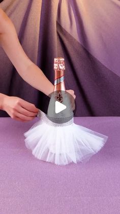 a person holding a bottle of champagne on top of a white tutule skirt