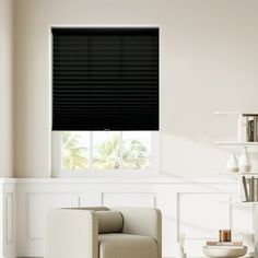 a living room with white walls and black blinds on the window sill, in front of a beige chair