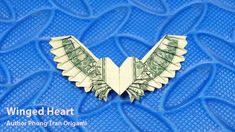 an origami bat made out of dollar bills on blue background with text winged heart