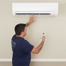 a man is working on an air conditioner in his living room while holding a remote control