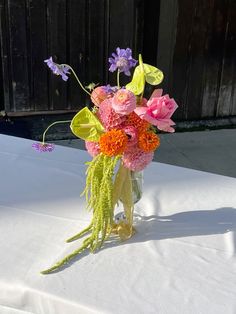 a vase filled with flowers sitting on top of a white table covered in snow next to a wooden fence