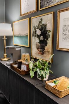 a living room with pictures on the wall and plants in vases next to it