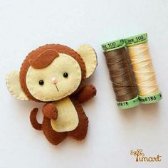 a stuffed monkey next to a spool of thread