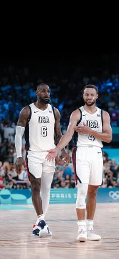 two basketball players standing on the court with their hands in each other's pockets