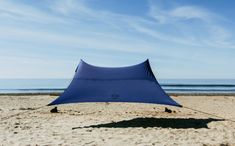 a blue tent sitting on top of a sandy beach