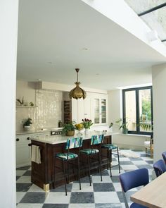 a kitchen with checkered flooring and an island in the center surrounded by blue chairs