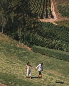 two people holding hands while walking in the grass