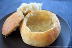 two pieces of bread on a black plate with blue table cloth behind it and one piece cut in half to show the inside