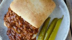 a sloppy joe sandwich on a plate with pickles