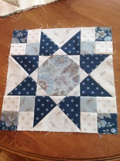 a wooden table topped with a blue and white patchwork quilt