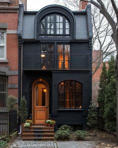 a black house with an arched window and wooden steps leading up to the front door