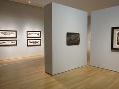 a man is walking through an art gallery with paintings on the wall and in the background