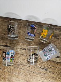 four shot glasses with stickers on them sitting on a wooden table next to each other