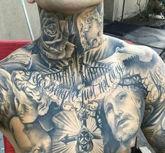 the back of a man's chest with tattoos on it and roses around his neck