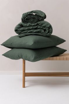 three pillows stacked on top of each other in front of a bench with a wooden frame