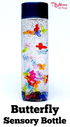 a bottle filled with lots of colorful candies on top of a white table next to the words butterfly sensory bottle