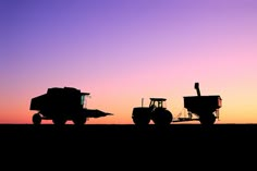 two farm equipment silhouetted against a purple and blue sky at sunset in the middle of nowhere