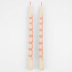 two white candles with pink rings on them