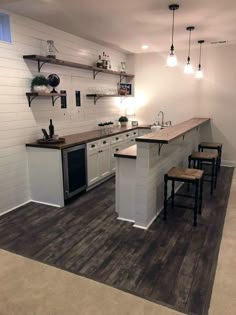 a kitchen with white walls and wooden floors, two bar stools on the counter