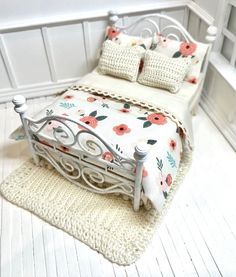 a white bed sitting on top of a wooden floor next to a rug covered in pillows