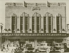 an old black and white photo of cars parked in front of a building