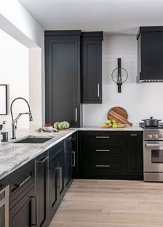 a kitchen with black cabinets and stainless steel appliances