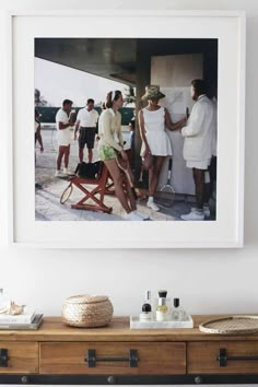 a group of people standing around in front of a framed photo on a white wall