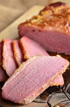 sliced meat sitting on top of a wooden cutting board next to another piece of meat