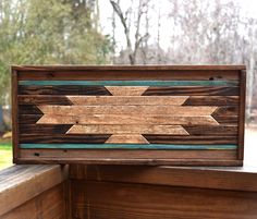 a wooden sign sitting on top of a wooden bench next to a forest filled with trees