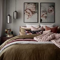 a bed with two pictures on the wall above it and a blanket draped over it