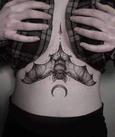 a woman's stomach with a bat and moon tattoo on the bottom part of her abdomen