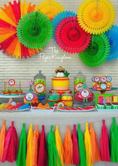 a table topped with lots of colorful paper fans and desserts on top of it