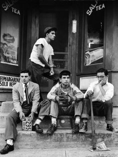 black and white photograph of four men sitting on steps with signs in front of them